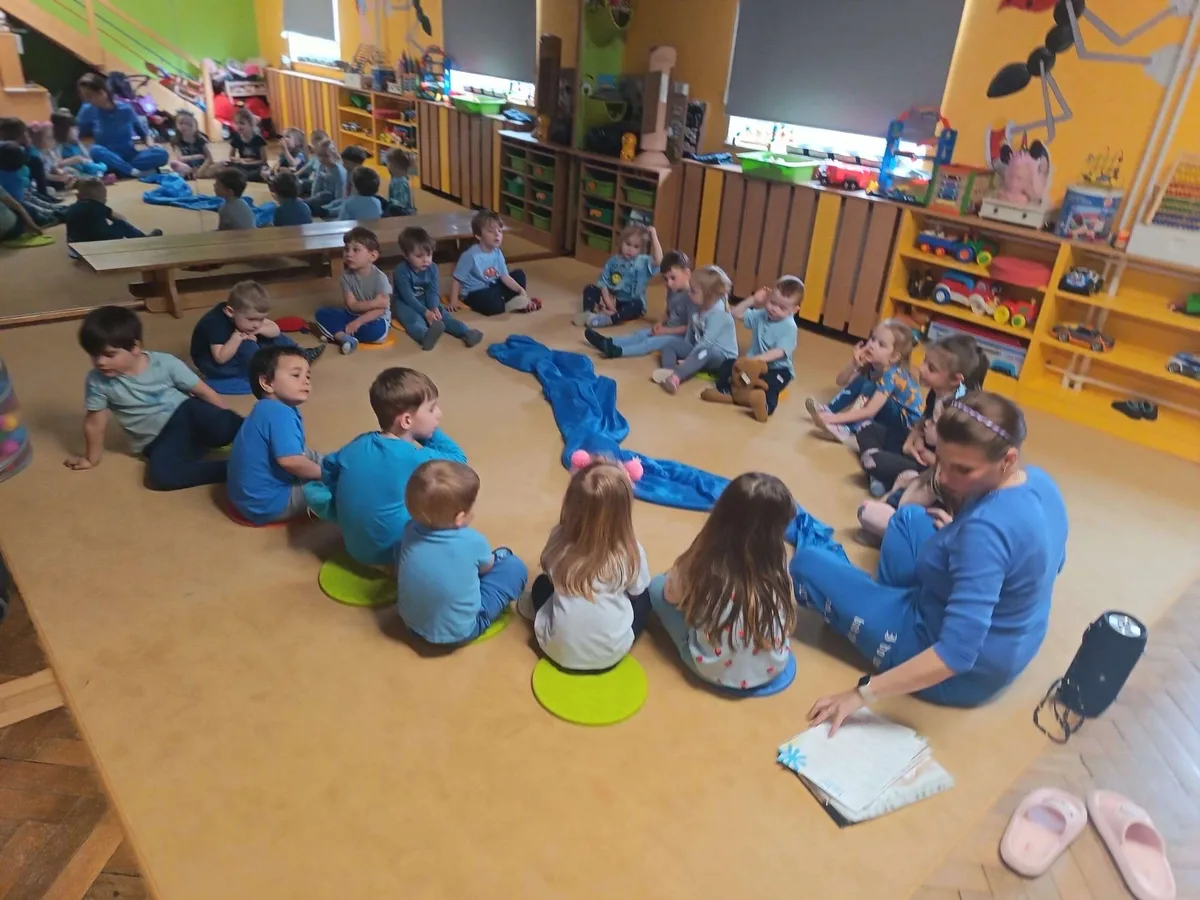 Děti sedí v kruhu na koberci při lekci angličtiny