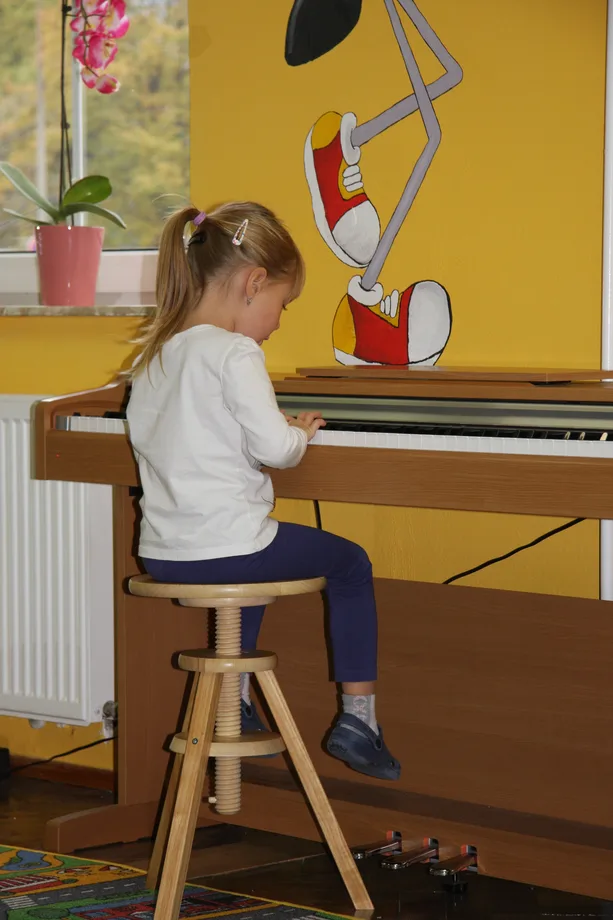 Holčička hraje na klavír v herně