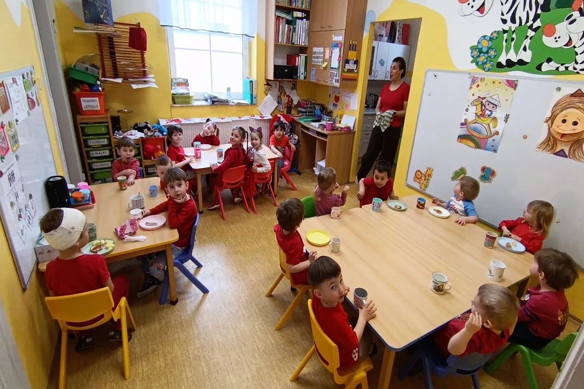Děti u stolečků ve třídě při svačině
